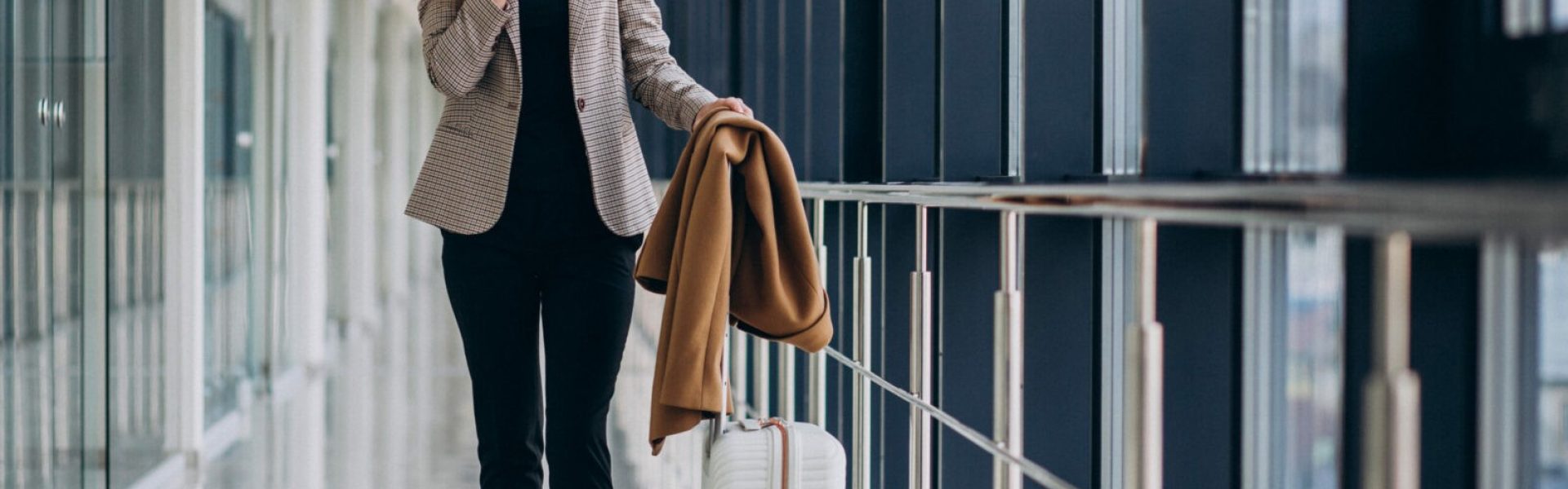 Business woman in terminal with travel bag talking on phone
